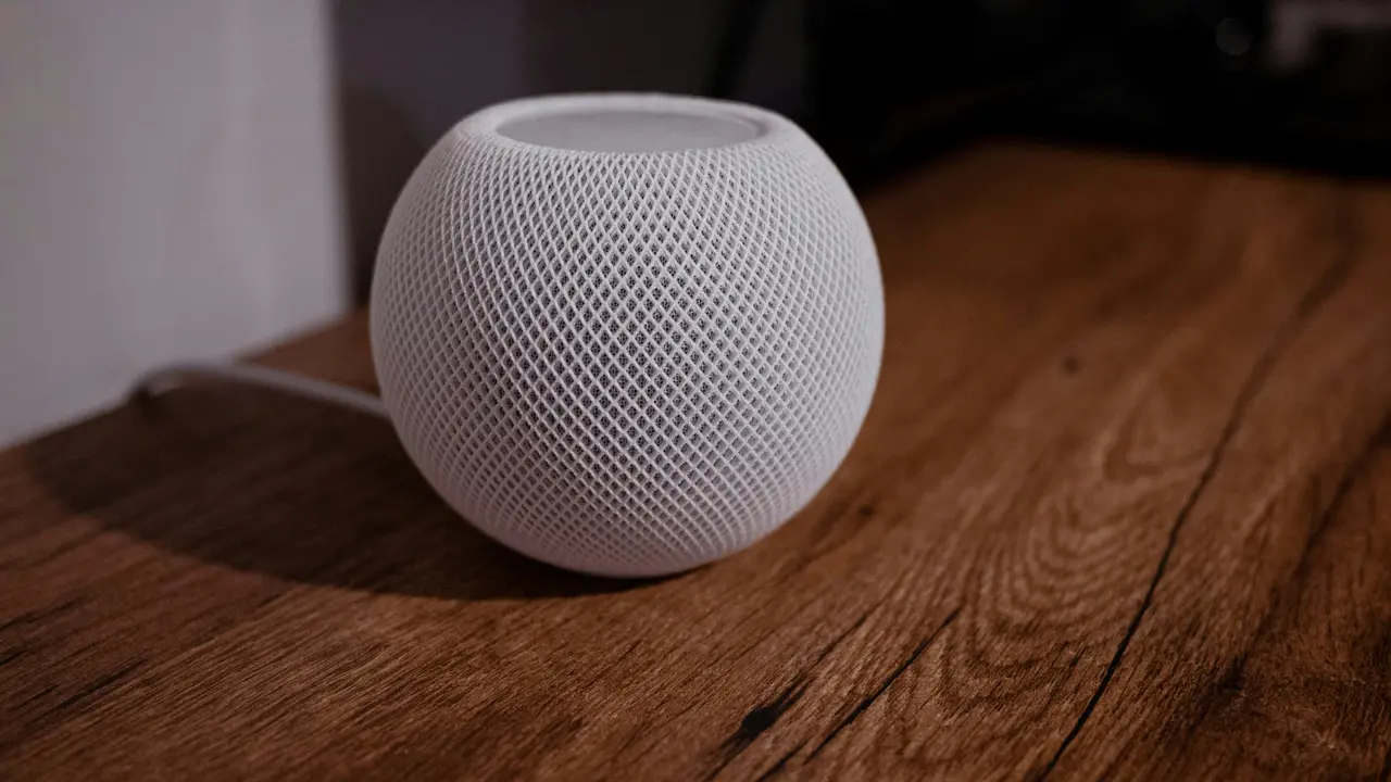 木のテーブルに置かれた白いHomePod mini（初代）